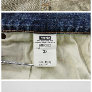 May include: Close-up of denim jeans with a Wrangler label. The label reads "CRAFTED WITH PRIDE". The size tag indicates a size 33. The care label shows washing instructions and fabric composition: 98% cotton, 2% polyurethane.