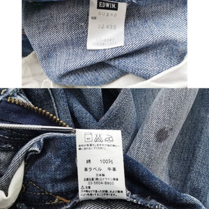May include: Close-up of blue denim jeans with a visible tag. The tag reads "EDWIN" and "503SD" with a size of 32x33. The jeans are made of 100% cotton. The image also shows care instructions and Japanese text.