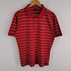 Puede incluir: Una taza de cer&aacute;mica blanca con un asa negra y el texto "But First, Coffee" en negrita negra. La taza est&aacute; llena de un l&iacute;quido oscuro, probablemente caf&eacute;, y se encuentra sobre una superficie clara.