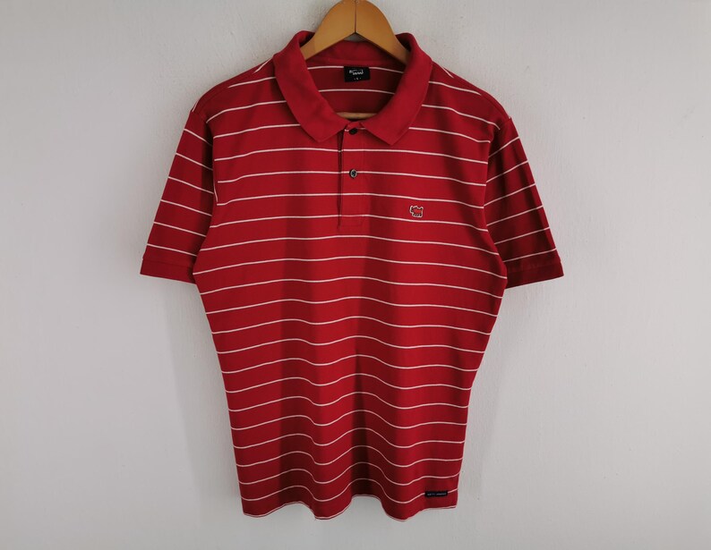 Puede incluir: Una taza de cer&aacute;mica blanca con un asa negra y el texto "But First, Coffee" en negrita negra. La taza est&aacute; llena de un l&iacute;quido oscuro, probablemente caf&eacute;, y se encuentra sobre una superficie clara.