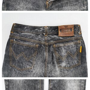 May include: Acid wash denim jeans with a button and zipper closure. The jeans have front and back pockets with orange stitching and a leather "EDWIN" brand patch. The jeans are folded at the bottom.