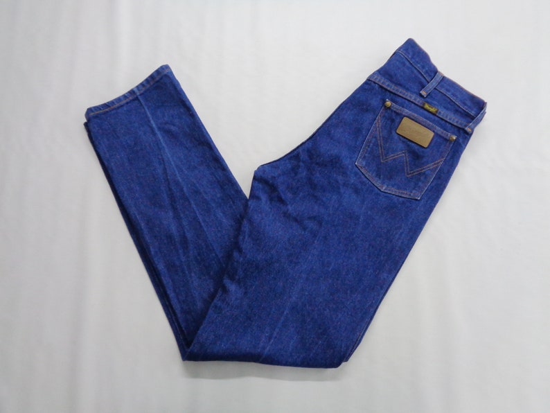 May include: A pair of blue denim jeans with a classic five-pocket design. The jeans feature a brown leather patch on the back pocket with the brand logo. The jeans are made of a durable denim fabric and have a straight leg cut.