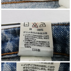 May include: Close-up of denim jeans label with Japanese text. The label shows measurements: waist 81 cm, hip 98 cm, and size 32. The label also includes washing instructions and the brand name.