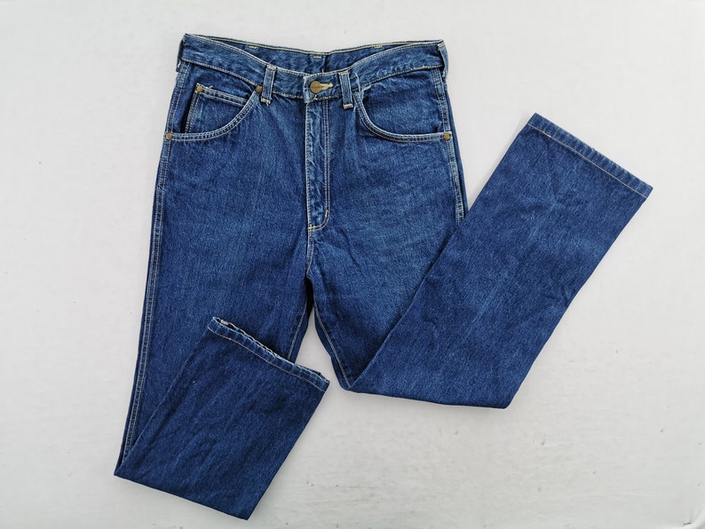 May include: A pair of classic blue denim jeans, featuring a button and zipper closure, front and back pockets, and belt loops. The jeans are folded neatly, showcasing the traditional five-pocket design and a straight leg cut.