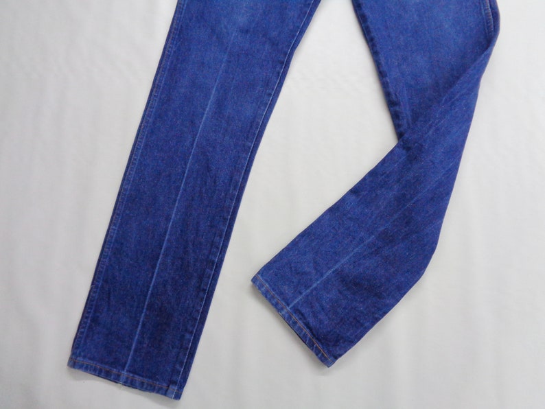 May include: A pair of classic blue denim jeans. The jeans have a straight leg design and are made of a medium-weight denim fabric. The image shows the jeans laid flat, showcasing the front and part of the leg.