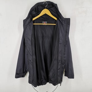 May include: Black hooded jacket with a mesh lining, hanging on a wooden hanger. The jacket has a zipper closure, a drawstring at the bottom, and a small logo on the chest. The jacket is displayed against a white background.