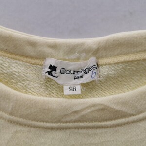May include: Close-up of a pale yellow sweatshirt with a crew neck. A white label with the text "Courr&egrave;ges paris" and a logo is sewn into the neckline. The label also has the number "9R" printed on it.