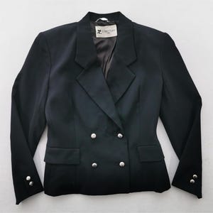 May include: A black double-breasted blazer with silver buttons. The blazer has a notched lapel, two front pockets, and buttons on the sleeves. The label reads "Carrige".