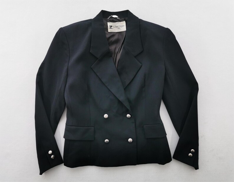 May include: A black double-breasted blazer with silver buttons. The blazer has a notched lapel, two front pockets, and buttons on the sleeves. The label reads "Carrige".