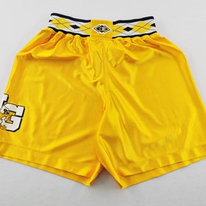 May include: Bright yellow athletic shorts with a contrasting waistband featuring a diamond pattern in black, white, and yellow. The shorts have a logo on the left leg. The shorts are made of a shiny material.