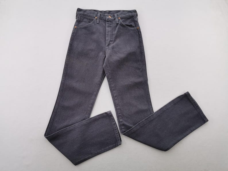 May include: A pair of dark gray denim jeans, laid flat. The jeans have a classic five-pocket design with a button and zipper closure. The fabric appears to be a medium weight denim.