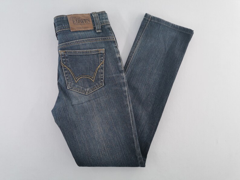 K&ouml;nnte beinhalten: Blaue Jeans aus Denim mit geradem Schnitt, klassischem F&uuml;nf-Taschen-Design und einem braunen Lederaufn&auml;her am hinteren Bund mit dem Text Edwin. Die Jeans hat Kontrastn&auml;hte und eine verwaschene Optik sowie G&uuml;rtelschlaufen am Bund.