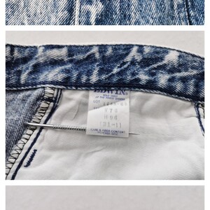 May include: Close-up of acid wash denim jeans. The jeans have a faded blue and white pattern. The Edwin brand label is visible. The jeans have a button and zipper closure. The jeans have a tag with the size and care instructions.
