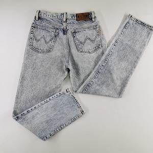 K&ouml;nnte beinhalten: Jeans aus Acid-Wash-Denim mit klassischem F&uuml;nf-Taschen-Design. Die Jeans haben ein hellblaues und graues Marmormuster, einen braunen Lederaufn&auml;her und das Wrangler-Logo auf den Ges&auml;&szlig;taschen. Vintage-Stil.