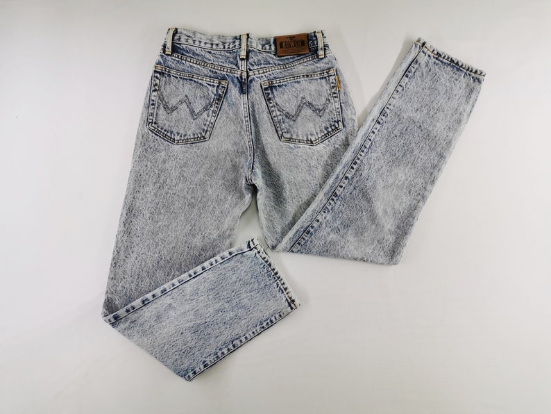 K&ouml;nnte beinhalten: Jeans aus Acid-Wash-Denim mit klassischem F&uuml;nf-Taschen-Design. Die Jeans haben ein hellblaues und graues Marmormuster, einen braunen Lederaufn&auml;her und das Wrangler-Logo auf den Ges&auml;&szlig;taschen. Vintage-Stil.