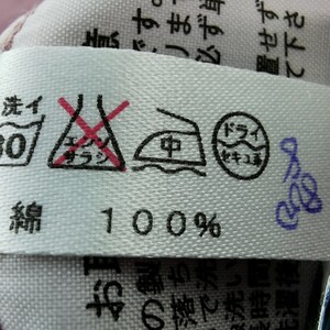 May include: A white fabric tag with care symbols and Japanese text. Symbols include a washtub with "30" inside, a crossed-out triangle, an iron, and a circle. The tag reads "100%" and has additional Japanese text.
