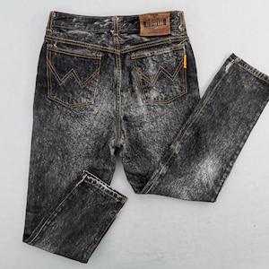 May include: Acid wash black denim jeans with orange stitching and a classic five-pocket design. The jeans feature the Edwin brand label on the back and a yellow tag. A stylish and timeless addition to any wardrobe.