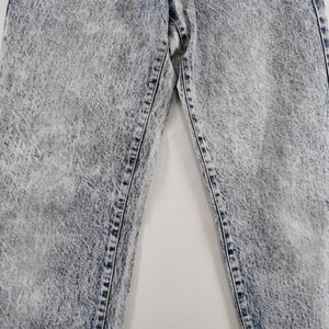 K&ouml;nnte beinhalten: Nahaufnahme einer Jeans aus Acid-Wash-Denim. Die Jeans hat ein hellblaues und wei&szlig;es, gesprenkeltes Muster mit sichtbaren N&auml;hten und Steppn&auml;hten. Das Bild konzentriert sich auf den oberen Teil der Jeans und zeigt die Textur und den Stil.