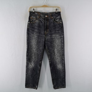 May include: Acid wash denim jeans with a high waist and straight leg. The jeans are a dark gray color with lighter gray, mottled patterns throughout. They are hanging on a wooden hanger against a white background.