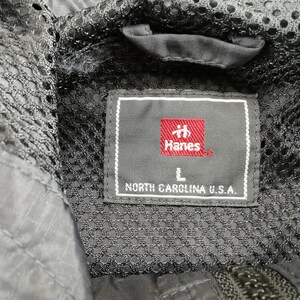 May include: Close-up of a black jacket's interior, featuring a mesh lining and a label. The label, with the Hanes logo in red, indicates size L and states "NORTH CAROLINA U.S.A."