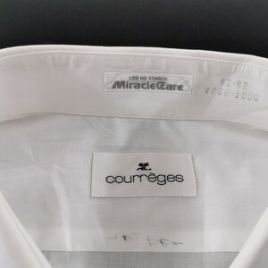 May include: Close-up of a white dress shirt collar with the brand label "courr&egrave;ges" visible. The shirt has a "Miracle Care" label and size markings "42-82 VP20-1000". The shirt is made of a smooth, likely cotton, fabric.