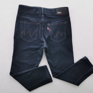 K&ouml;nnte beinhalten: Dunkelblaue Jeans aus Denim mit klassischem F&uuml;nf-Taschen-Design. Mit Lederaufn&auml;her mit Markennamen und rotem Etikett auf der Ges&auml;&szlig;tasche. Die Jeans hat einen geraden Beinverlauf und einen Knopf- und Rei&szlig;verschluss.