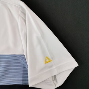 May include: White and blue short-sleeve polo shirt. The shirt features a white upper section, a blue striped middle section, and a black lower section. A yellow triangle logo with a rooster is on the sleeve.