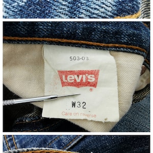 May include: Close-up of vintage denim jeans with a metal button marked "359". The Levi's brand label is visible, along with a size tag indicating a W32 waist. The fabric is a classic blue denim.