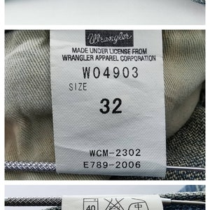May include: Close-up of blue denim jeans with yellow stitching. The jeans have a size 32 label and the Wrangler logo. The care label indicates the jeans are 100% cotton and made in China.