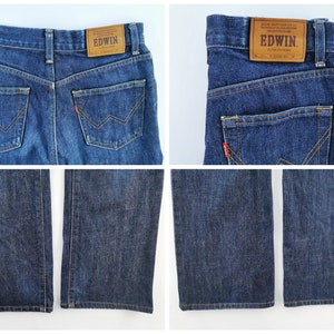 May include: Dark blue denim jeans with a classic five-pocket design. Features include a leather patch with "EDWIN" branding and a red logo tab. The jeans have a straight leg cut and are made of a durable denim fabric.