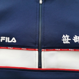 May include: Navy blue athletic jacket with a white stripe and red trim. The jacket features the FILA logo in white on the left chest and Japanese characters on the right chest. A full-length zipper runs down the center.