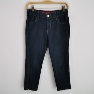 K&ouml;nnte beinhalten: Dunkelblaue Jeans an einem Holzb&uuml;gel. Die Jeans haben ein klassisches F&uuml;nf-Taschen-Design mit Knopf- und Rei&szlig;verschluss. Die Jeans sind im Straight-Leg-Stil gehalten.