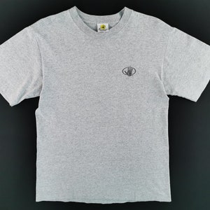 May include: A heather gray t-shirt with a crew neck and short sleeves. The shirt features a small, black logo on the left chest. The logo is a hand inside a circle. The shirt is made of a soft, comfortable material.