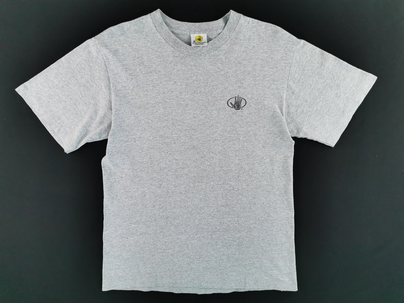 May include: A heather gray t-shirt with a crew neck and short sleeves. The shirt features a small, black logo on the left chest. The logo is a hand inside a circle. The shirt is made of a soft, comfortable material.
