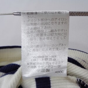 May include: A white fabric garment care label with Japanese text printed in black, featuring instructions for washing and maintenance. The label is attached to a ribbed knit textile with alternating horizontal navy blue and white stripes.