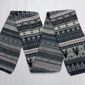 Könnte beinhalten: Gestrickter Schal in Grün-, Weiß- und Marineblautönen mit geometrischem und Sternmuster. Der Schal hat ein Etikett mit der Aufschrift "BEAMS". Der Schal ist etwa 152 cm lang.