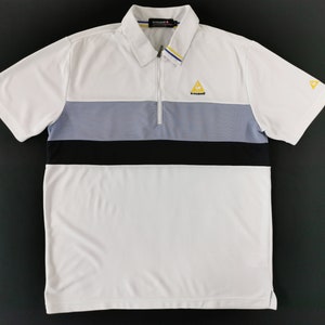 May include: White polo shirt with a color block design featuring a gray and black stripe across the chest. The shirt has a zipper closure, short sleeves, and a small yellow logo on the chest and sleeve.
