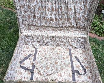 May include: An open vintage suitcase with a brown tweed exterior and a paisley patterned lining. The suitcase has a brown leather handle and a brass latch.
