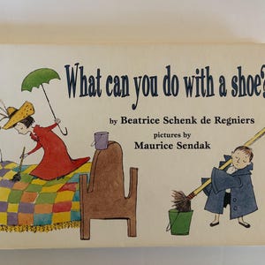 May include: A vintage children's book cover with the title "What can you do with a shoe?" by Beatrice Schenk de Regniers, illustrated by Maurice Sendak. The cover features whimsical illustrations of a person in a red dress and a child with a broom.