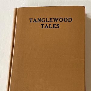 May include: A hardcover book with a tan cover. The title "TANGLEWOOD TALES" is printed in black, centered at the top. The book's spine is visible on the left side. The cover has a slightly textured appearance.