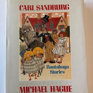May include: A hardcover book titled "Rootabaga Stories Part One" by Carl Sandburg, illustrated by Michael Hague. The cover features a colorful illustration of whimsical characters in a town setting.