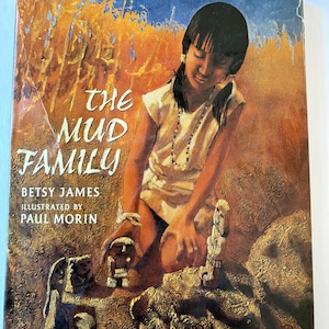 Könnte beinhalten: Das Cover des Buches "The Mud Family" zeigt ein junges Mädchen, das kniet und von Tonskulpturen umgeben ist. Der Titel und der Name des Autors sind sichtbar. Das Kunstwerk hat eine warme Farbpalette mit Erdtönen und blauem Himmel.
