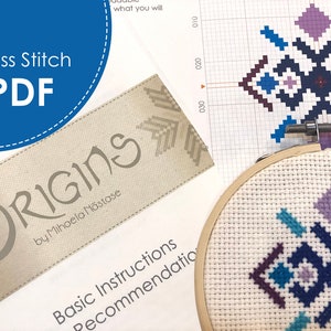 May include: A cross stitch pattern with a geometric design in shades of blue, purple, and brown. The pattern is displayed on a white grid with numbers along the side. The pattern is also stitched on a piece of white fabric in a wooden embroidery hoop. The pattern is titled "Origins 27" and is by Mihaela Năstase.