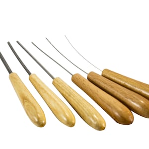 May include: Six wooden handled tools with metal tips. The tools are arranged in a row, with the handles pointing to the right. The handles are a light brown color, and the metal tips are silver.