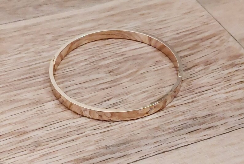May include: A gold-toned bangle bracelet with a hammered texture.