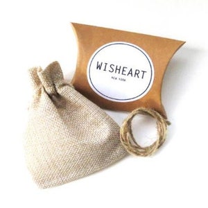 May include: A small burlap bag with a drawstring closure, a brown cardboard box with a white circle label that says "WISHHEART NEW YORK", and a roll of twine.