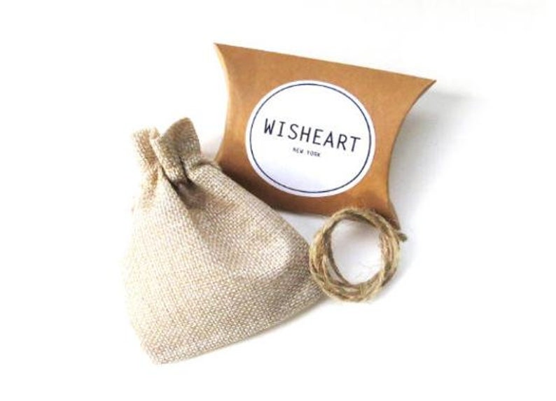 May include: A small burlap bag with a drawstring closure, a brown cardboard box with a white circle label that says "WISHHEART NEW YORK", and a roll of twine.