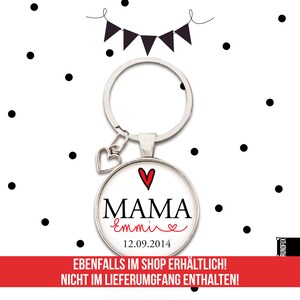 May include: A silver key chain with a heart charm and a round glass charm. The glass charm has a white background with black text that says "MAMA Emmive" and a red heart. The date "12.09.2014" is printed below the text.