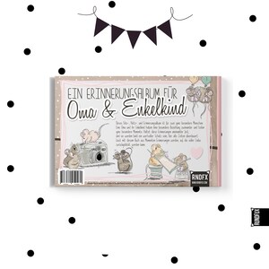 以下が含まれることがあります： 「EIN ERINNERUNGSALBUM F&Uuml;R Oma & Enkelkind」のテキストが入った思い出アルバム。カメラ、風船、裁縫道具を持ったネズミのイラストが特徴です。アルバムはピンクとベージュの表紙で、黒い水玉模様があります。