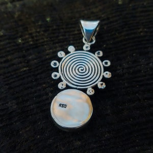May include: Silver pendant with a spiral design and a circle with the number 925 stamped on it.